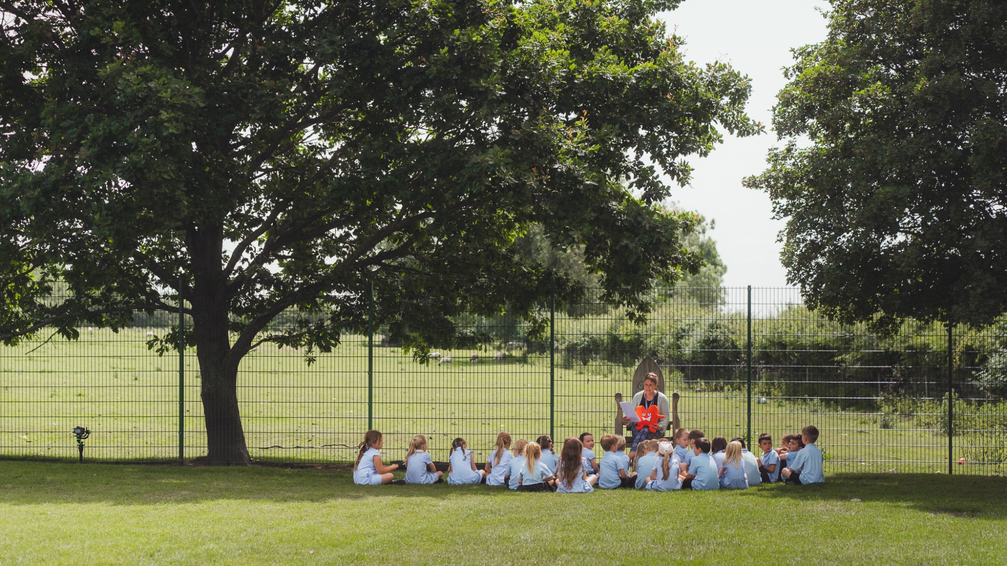 students sat on field listening to book read